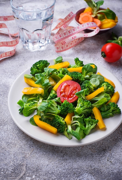 Foto gezonde plantaardige salade, water en meetlint