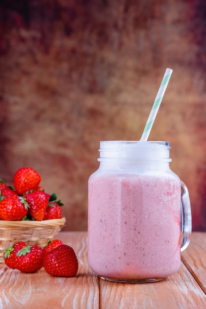 Gezonde roze smoothie met aardbei in glazen potten..