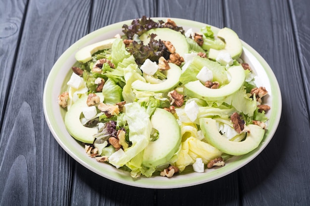 Gezonde salade met avocado, walnoten en kaas. Veganistisch eten.