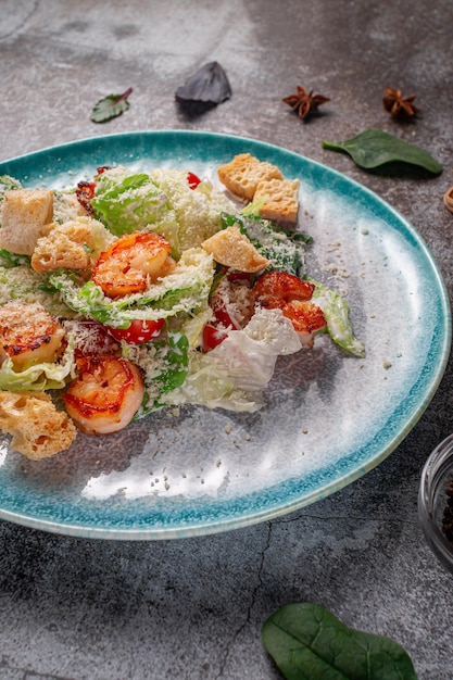 Gezonde salade met gebakken garnalen, greens en croutons in een bord tegen een grijze stenen tafel. Een gezond ontbijt in een restaurant