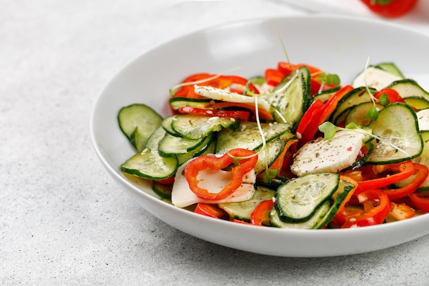 Gezonde salade met gesneden komkommers feta kaas paprika's in een witte plaat Verse groene snack