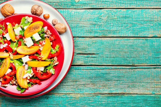 Gezonde salade met persimmon en fetakaas Seizoenssalade op houten tafel Ruimte voor tekst