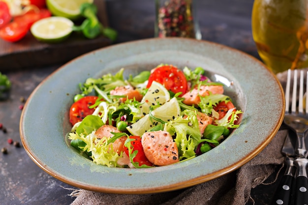 Gezonde salade met vis. Gebakken zalm, tomaten, limoen en sla.