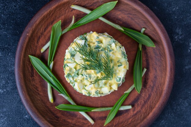 Gezonde salade van groene wilde prei, gepocheerd ei en zure room in plaat, close-up. Daslooksalade met gekookte eieren