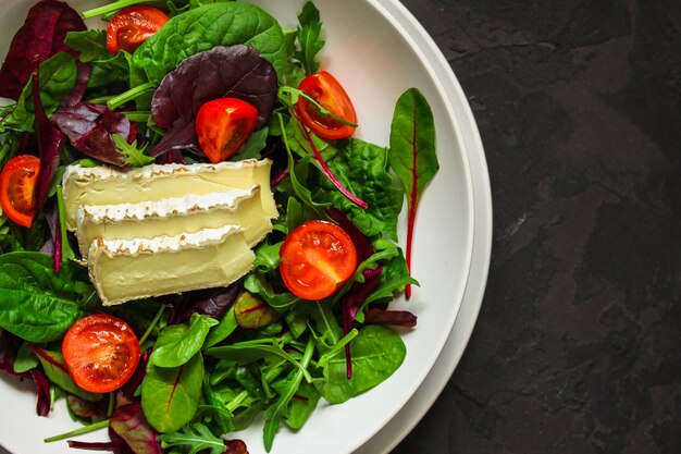 Gezonde saladebladeren in een witte plaat en een kaas (meng microgroente, sappige snack). voedsel achtergrond