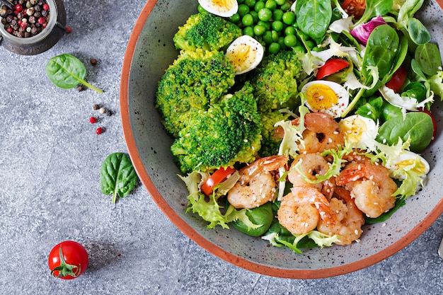 Gezonde saladeplaat. Vers zeevruchtenrecept. Gegrilde garnalen en verse groentesalade, ei en broccoli. Gegrilde garnalen.