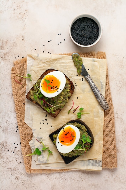 Gezonde sandwich met avocado, eieren en microgreens op toast op een serveerschaal voor het ontbijt. Gezonde voeding dieet concept. Bovenaanzicht