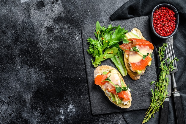 Gezonde sandwich met avocado en zalm. Spinazie en rucola salade.