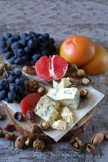 Gezonde snack op een houten dienblad. Kaas, noten en fruit. Keto-dieet. Keto-snack.