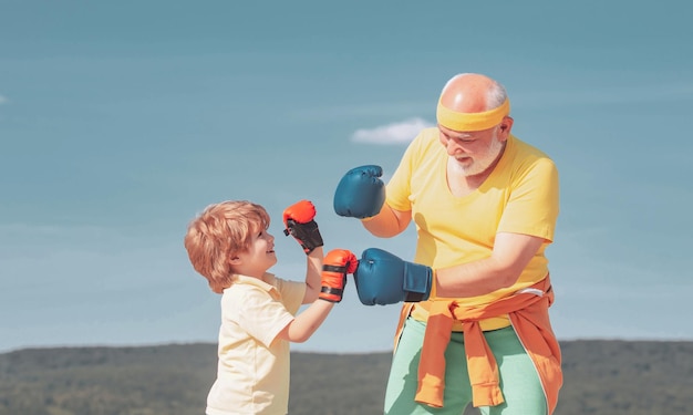 Gezonde vechter Grootvader en kleinzoon met bokshandschoenen Grootvader en kleinzoon doen bokstraining
