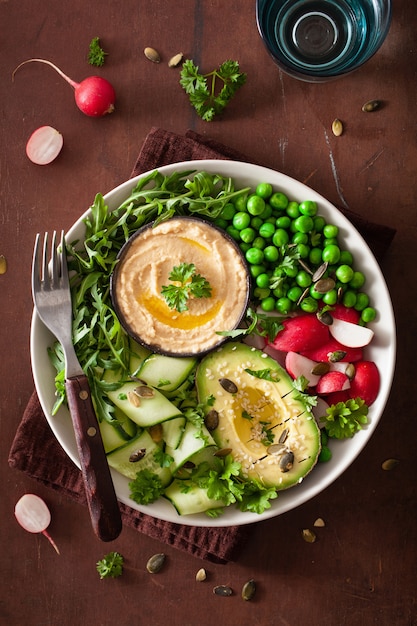 Gezonde vegan lunchkom met avocaco komkommer hummus erwten radijs