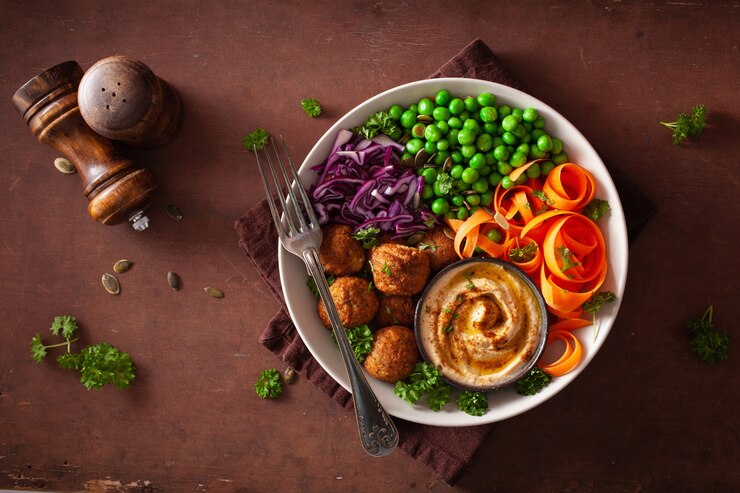 Foto gezonde vegan lunchkom met falafel hummus wortel linten kool en erwten