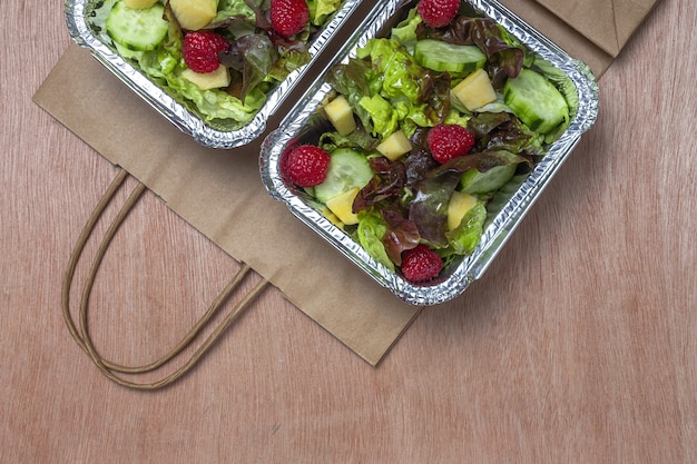 Gezonde veganistische afhaalsalade in aluminium bak of bezorging.