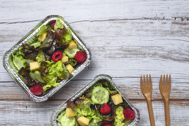 Gezonde veganistische afhaalsalade in aluminium bak of bezorging.