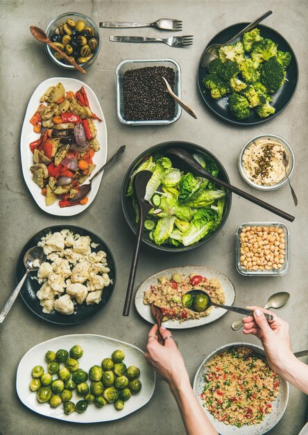 Gezonde veganistische gerechten en vrouwenhanden die couscous van bord nemen