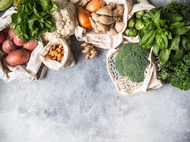 Gezonde veganistische ingrediënten voor het koken. Verschillende schone, gezonde groenten en kruiden in geweven zakken. Producten uit de markt zonder plastic. Zero waste concept flat lag. Ruimte kopiëren