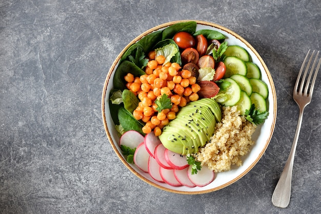 Gezonde vegetarische salade met kikkererwten, quinoa, komkommer, radijs en avocado