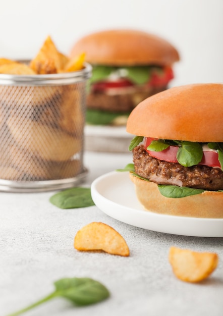 Gezonde vegetarische vleesvrije hamburgers op ronde snijplank met groenten op lichte tafel met aardappelpartjes.