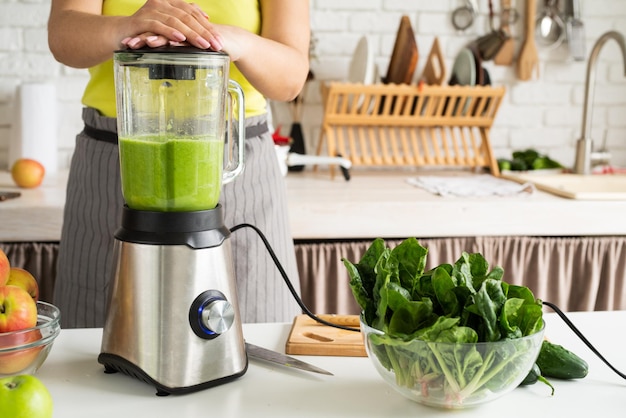 Gezonde voeding bereiden Gezond eten en diëten Jonge brunette vrouw die groene smoothie maakt thuis keuken