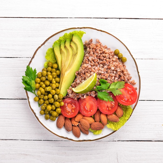 Gezonde voeding Boekweit cherry tomaten avocado's amandelen en groene erwten Op een houten achtergrond Bovenaanzicht Vrije ruimte voor uw tekst