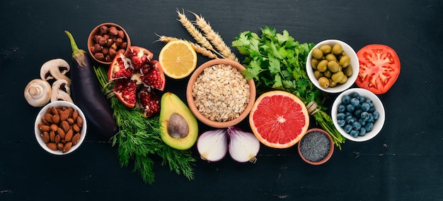 Foto gezonde voeding clean eating selectie groenten fruit noten bessen en paddenstoelen peterselie kruiden op een zwarte achtergrond vrije ruimte voor tekst