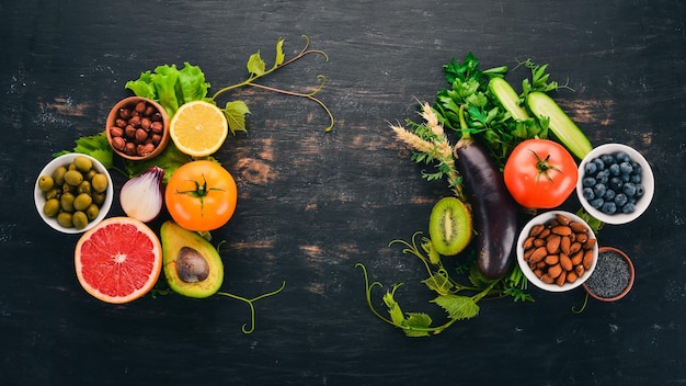 Gezonde voeding clean eating selectie Groenten fruit noten bessen en paddenstoelen peterselie kruiden Op een zwarte achtergrond Vrije ruimte voor tekst