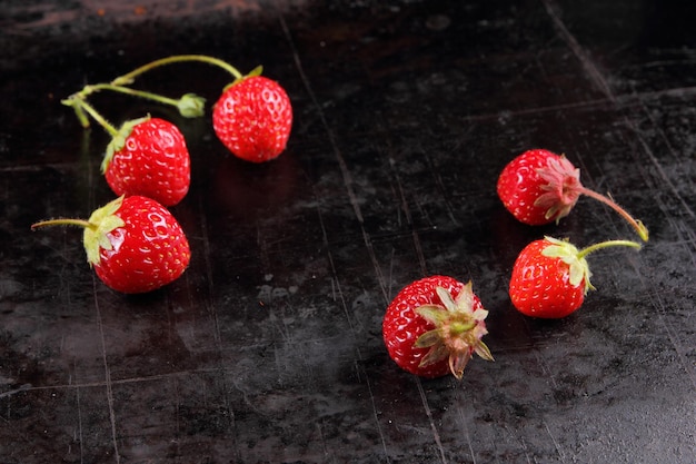 Gezonde voeding concept Rode sappige zoete aardbeien met twijgen op een zwarte achtergrond Close-up van rode bessen