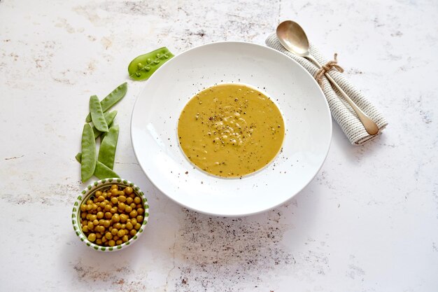 Foto gezonde voeding creamsoep met groene erwten in een wit keramiek bord op een stenen tafel het concept van dieeteten