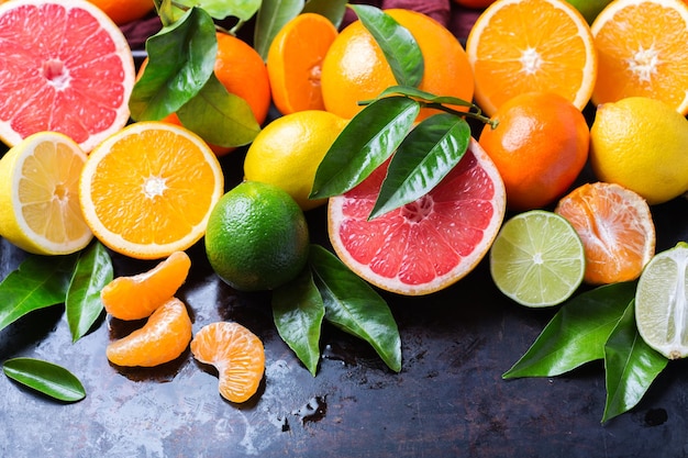 Gezonde voeding dieet voeding natuur concept Citrusvruchten vitamine achtergrond Oranje grapefruit mandarijn limoen citroen met bladeren op een grunge zwarte tafel