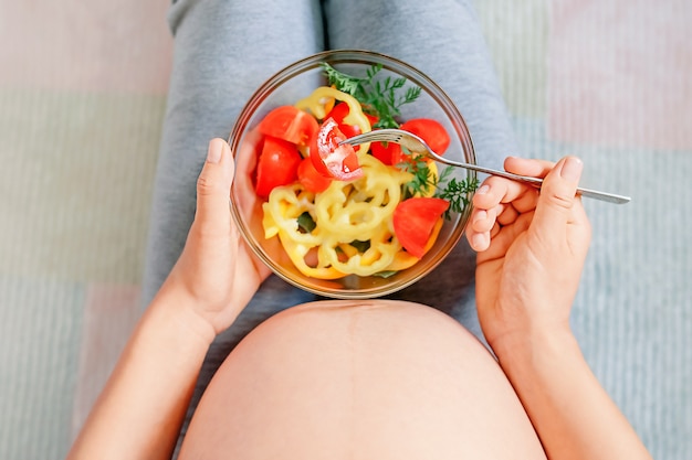 Gezonde voeding en zwangerschap. buik en groentesalade van zwangere vrouw