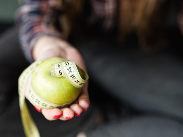 Gezonde voeding eten gewichtsverlies en fit lichaam biologische natuurlijke producten voor evenwichtige voeding vrouw met verse appel met gedraaid meetlint in de hand