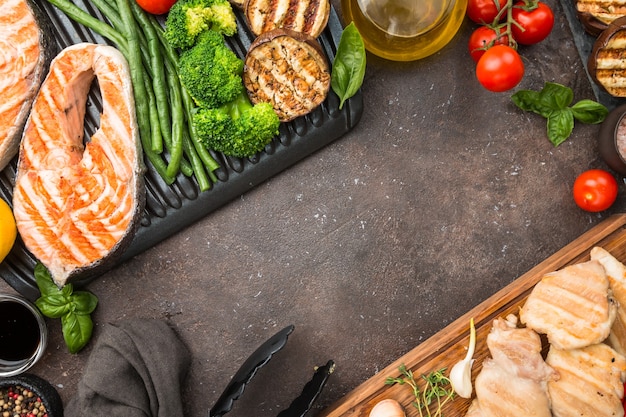 Gezonde voeding gegrilde zalm steak, kip en groenten over donkere ondergrond, bovenaanzicht