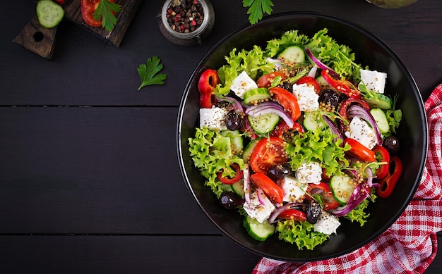 Gezonde voeding Griekse salade met komkommer tomaten zoete peper sla rode ui feta kaas en olijven Top view kopieerruimte