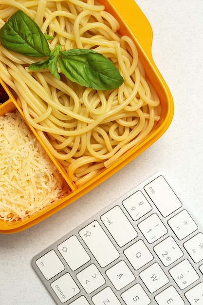 Gezonde voeding in plastic bakjes klaar om te eten met zelfgemaakte spaghetti met tomaat, kaas en basilicum op de werktafel. Italiaans eten. Wegnemen.