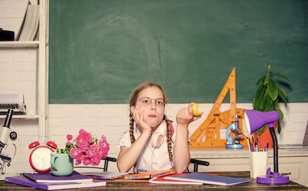 Gezonde voeding klein meisje klaar om appel te eten Slim kind concept gezond eten is goed terug naar school Einstein klein geniaal kind in de klas Lunchtijd digitaal tijdperk met moderne technologie