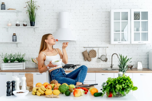 Gezonde voeding Mooie vrouw die verse biologische vegetarische salade eet in moderne keuken Gezond eten, voedsel en levensstijl concept Gezondheid schoonheid dieet concept