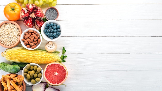 Gezonde voeding op een witte houten tafel. Verse groenten, fruit, noten, bessen, champignons. Bovenaanzicht. Vrije ruimte voor tekst.