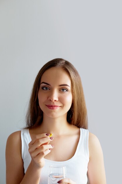 Gezonde voeding. Portret van mooie glimlachende jonge vrouw vitamine pil te nemen