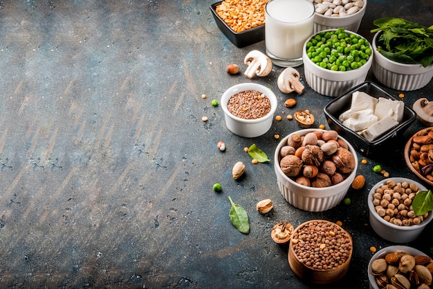 Gezonde voeding veganistisch voedsel, plantaardige eiwitbronnen: tofu, veganistische melk, bonen, linzen, noten, sojamelk, spinazie en zaden. Bovenaanzicht op witte tafel.