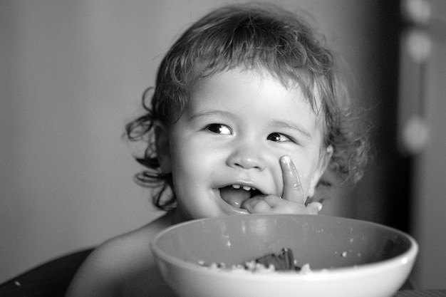 Gezonde voeding voor kinderen grappige baby die zelf voedsel eet met een lepel op de keuken