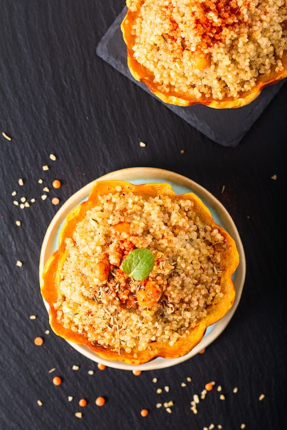 Gezonde voeding zelfgemaakte biologische Quinoa Gevulde zoete knoedel squash op zwarte leisteen