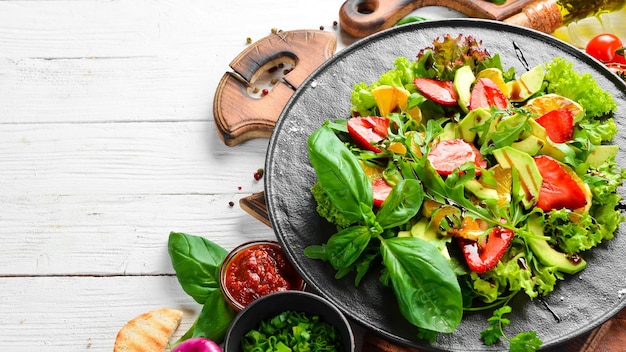 Gezonde voedselsalade van rucola, avocado, aardbei en sinaasappel Bovenaanzicht Vrije ruimte voor uw tekst