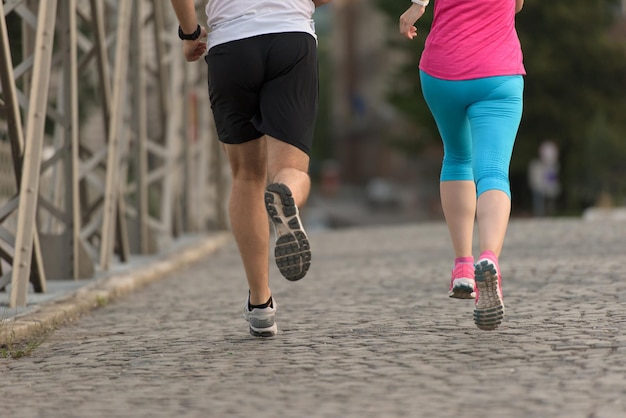 gezonde volwassen paar joggen in de stad in de vroege ochtend met zonsopgang op de achtergrond