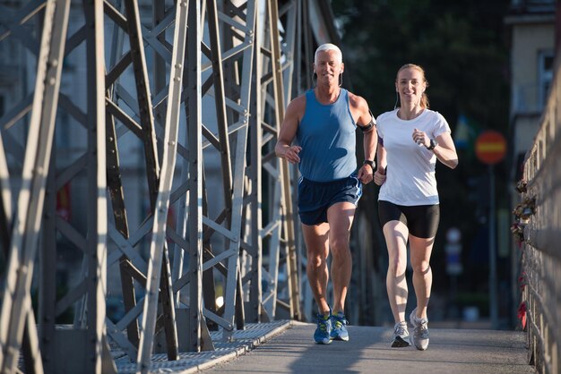 gezonde volwassen paar joggen in de stad in de vroege ochtend met zonsopgang op de achtergrond