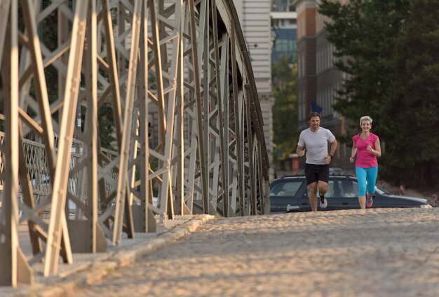 gezonde volwassen paar joggen in de stad in de vroege ochtend met zonsopgang op de achtergrond