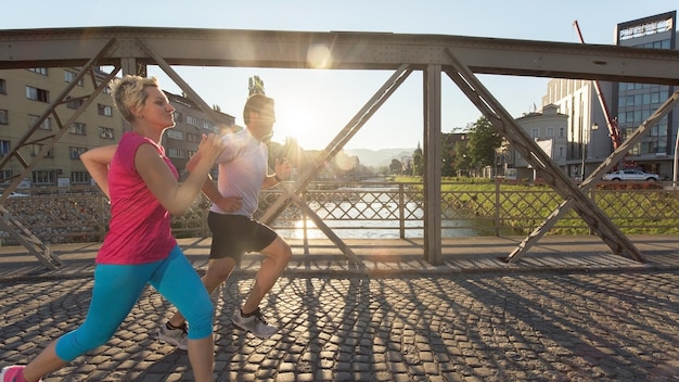 gezonde volwassen paar joggen in de stad in de vroege ochtend met zonsopgang op de achtergrond