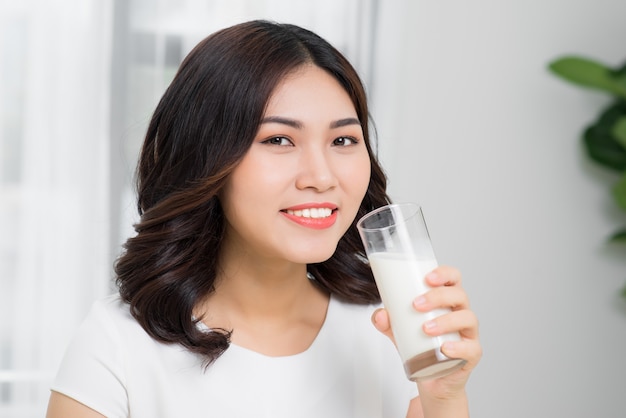 Gezonde vrouw drinkt melk uit een glas geïsoleerd op een witte achtergrond.