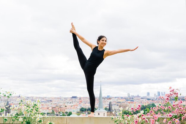 Gezonde vrouw in een sportkleding die buiten yoga beoefent, oefeningen doet, portret van volledige lengte.