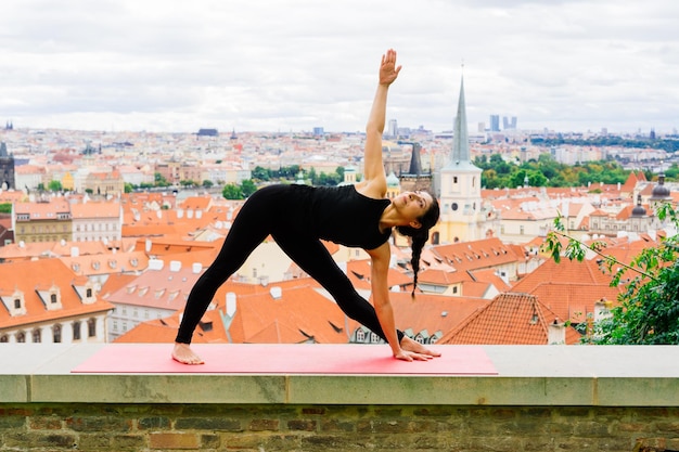 Gezonde vrouw in een sportkleding die buiten yoga beoefent, oefeningen doet, portret van volledige lengte.