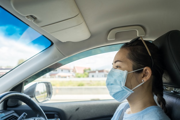 Gezonde vrouw met beschermend gezichtsmasker auto rijden